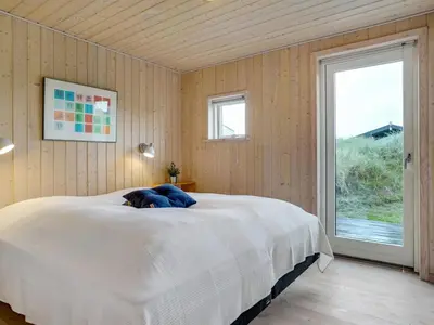 a bedroom with a large white bed with a window at Holiday Home Josten - 500m from the sea by Interhome in Saltum