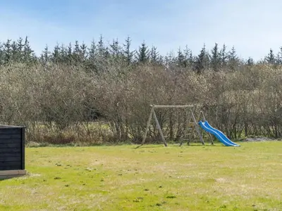 a playground with a blue slide in a field at Holiday Home Bentine - 1-6km from the sea by Interhome in Saltum
