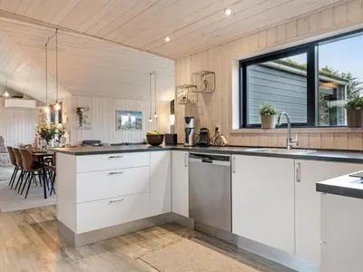 a kitchen with white cabinets and a large window at Holiday Home Javorka - 1-4km from the sea by Interhome in Saltum