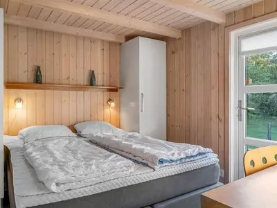 a bed in a room with wooden walls and a window at Holiday Home Mechthild - 2-7km from the sea by Interhome in Saltum