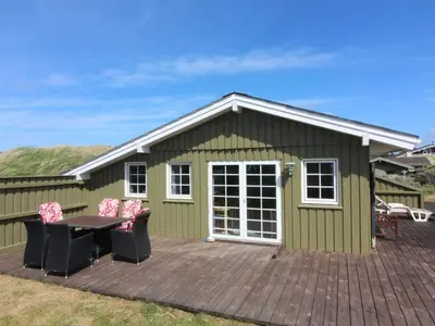 a green shed with a table and chairs on a deck at Holiday Home Arita - 250m from the sea by Interhome in Saltum
