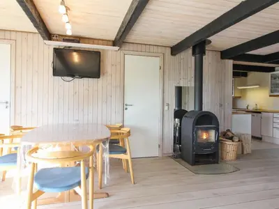 a living room with a table and a wood stove at Holiday Home Arita - 250m from the sea by Interhome in Saltum