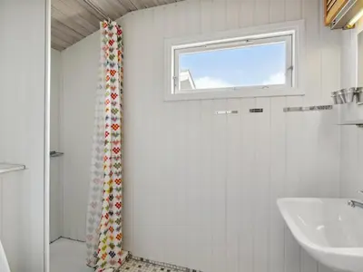 a white bathroom with a sink and a window at Holiday Home Aghe - 250m from the sea by Interhome in Saltum