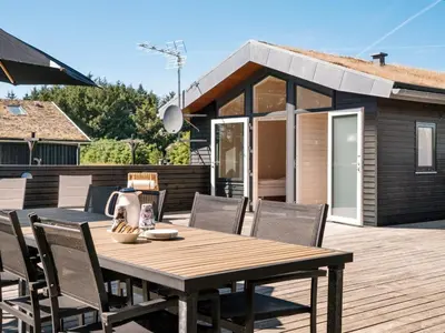 a wooden table and chairs on a deck with a house at Holiday Home Dorothe - 1-4km from the sea by Interhome in Saltum