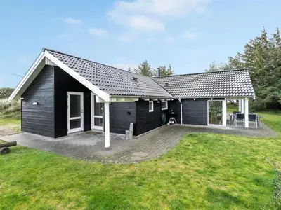 a black house with a large yard in front of it at Holiday Home Alhed - 650m from the sea by Interhome in Saltum