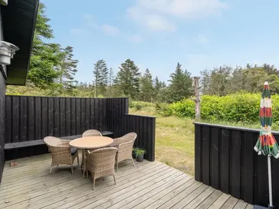 a patio with a table and chairs on a wooden deck at Holiday Home Jorek - 1-3km from the sea by Interhome in Saltum