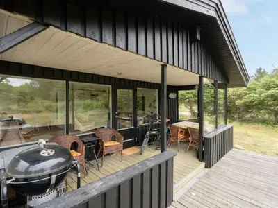 a black house with a grill on a deck at Holiday Home Jorek - 1-3km from the sea by Interhome in Saltum