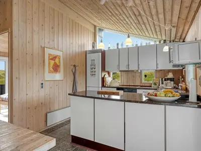 a kitchen with white cabinets and wooden walls at Holiday Home Rosemari - 260m from the sea by Interhome in Saltum