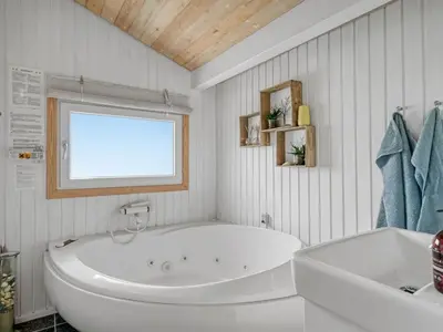 a white bathroom with a tub and a window at Holiday Home Rosemari - 260m from the sea by Interhome in Saltum