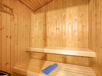 a wooden sauna with a blue towel sitting in it at Holiday Home Rosemari - 260m from the sea by Interhome in Saltum