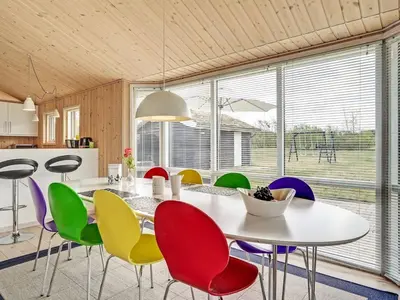 a dining room with a white table and colorful chairs at Holiday Home Frerich - 1-5km from the sea by Interhome in Saltum