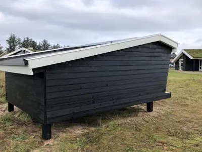 a black outhouse with a pitched roof in a field at Holiday Home Frerich - 1-5km from the sea by Interhome in Saltum