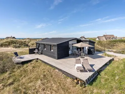 a black house on the beach with a deck at Holiday Home Felis - 200m from the sea by Interhome in Saltum