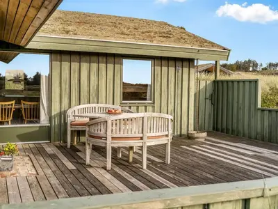a wooden deck with two benches and a table at Holiday Home Fransine - 480m from the sea by Interhome in Saltum