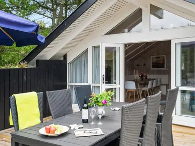 an outdoor table with chairs and a bottle of wine at Holiday Home Varpu - 1-6km from the sea by Interhome in Saltum