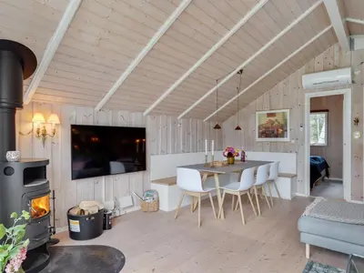 a kitchen and dining room with a table and a fireplace at Holiday Home Varpu - 1-6km from the sea by Interhome in Saltum