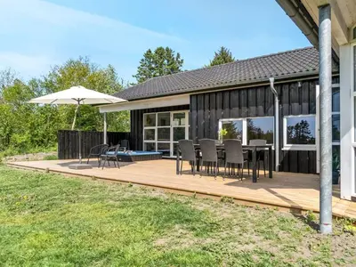 a deck with chairs and an umbrella on a house at Holiday Home Nayati - 2km from the sea by Interhome in Saltum