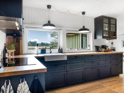 a kitchen with blue cabinets and a sink and a window at Holiday Home Ayelen - 600m from the sea by Interhome in Saltum