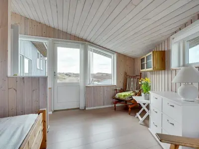 a bedroom with a bed and a table and a chair at Holiday Home Kulle - 200m from the sea by Interhome in Saltum