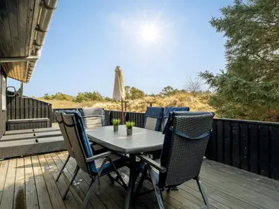 a table and chairs on the deck of a house at Holiday Home Gerwer - 700m from the sea by Interhome in Saltum