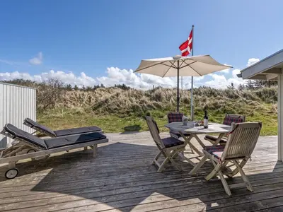 a patio with a table and chairs and an umbrella at Holiday Home Asser - 400m from the sea by Interhome in Saltum