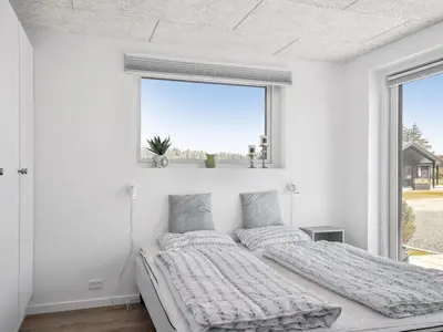 a white bedroom with two beds and a window at Holiday Home Fredrika - 1-5km from the sea by Interhome in Saltum