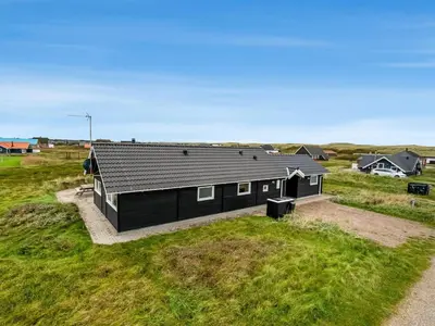 a black house sitting on top of a grass field at Holiday Home Sochyeta - 150m from the sea by Interhome in Harboør