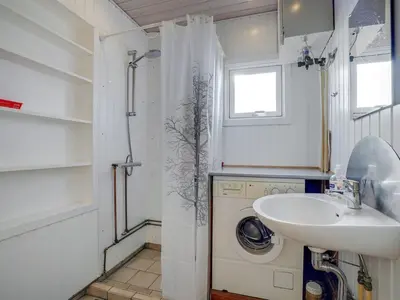 a bathroom with a sink and a washing machine at Holiday Home Soyala - 400m from the sea by Interhome in Harboør