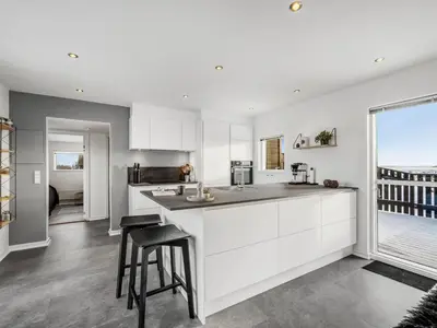 a kitchen with white cabinets and a large window at Holiday Home Damaskin - 300m from the sea by Interhome in Harboør