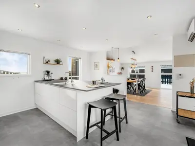 a white kitchen with a counter and stools at Holiday Home Damaskin - 300m from the sea by Interhome in Harboør