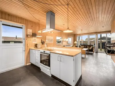 a kitchen with white cabinets and a large window at Holiday Home Odmar - 300m from the sea by Interhome in Harboør