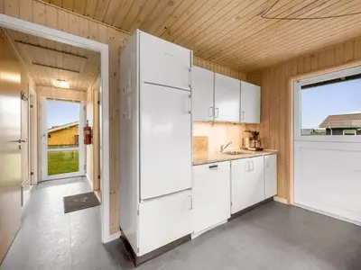 a kitchen with white cabinets and a large refrigerator at Holiday Home Odmar - 300m from the sea by Interhome in Harboør