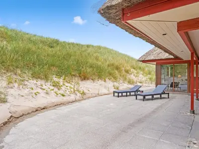 two blue chairs sitting on a patio next to a beach at Holiday Home Zora - 100m from the sea by Interhome in Harboør