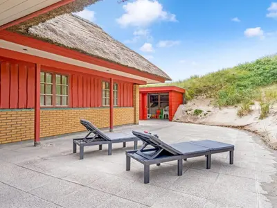 a house with two chairs and a building at Holiday Home Zora - 100m from the sea by Interhome in Harboør