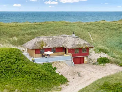 a red house in the sand near the ocean at Holiday Home Zora - 100m from the sea by Interhome in Harboør