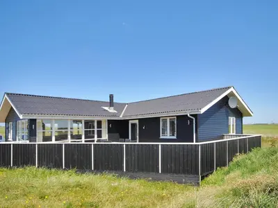 a blue house with a fence in front of it at Holiday Home Ernbiorn - from the sea by Interhome in Harboør