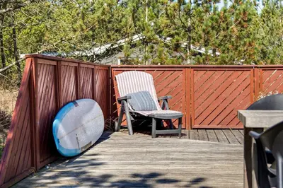 two chairs and a surfboard on a wooden deck at Cozy Holiday Home in Lovely Surroundings in Sønder Vorupør