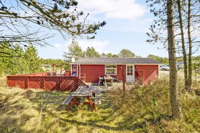 a red tiny house with a picnic table in the grass at Cozy Holiday Home in Lovely Surroundings in Sønder Vorupør