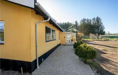 a yellow house with a sidewalk next to a building at 3 Bedroom Awesome Home In Thisted in Thisted