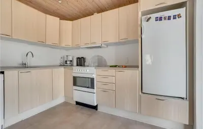 a kitchen with wooden cabinets and a white refrigerator at 3 Bedroom Awesome Home In Thisted in Thisted