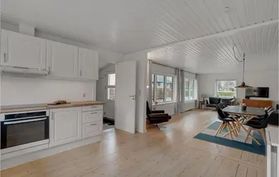 a kitchen with white cabinets and a table and chairs at Cozy Home In Nykøbing M With Wifi in Refshammer
