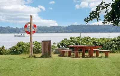 a picnic table and a life preserver next to a lake at Cozy Home In Nykøbing M With Wifi in Refshammer