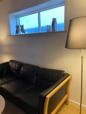 a black leather couch in a living room with a window at 200 m til havet - fri adgang til svømmehal in Thyborøn