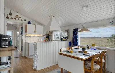 a kitchen with white cabinets and a table with chairs at 3 Bedroom Lovely Home In Lemvig in Lemvig