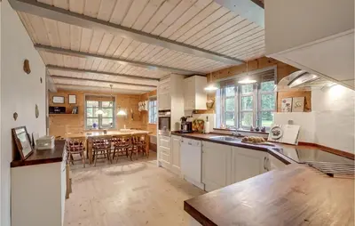 a kitchen with white cabinets and a table with chairs at 3 Bedroom Gorgeous Home In Højslev in Højslev