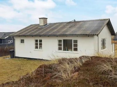 a white house with a black roof on a field at 4 person holiday home in Frøstrup in Frøstrup