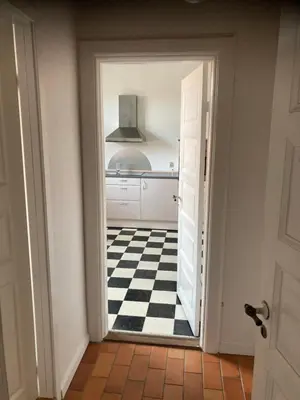an open door to a kitchen with a checkered floor at Store Sand in Vemb