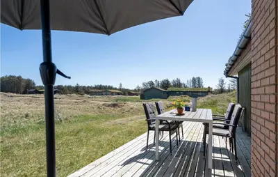 a table with chairs and an umbrella on a deck at Beautiful Home In Løkken With Wifi in Løkken