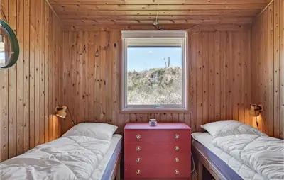 two beds in a wooden room with a window at Beautiful Home In Løkken With Wifi in Løkken
