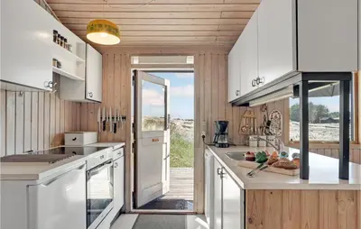 a kitchen with wooden walls and white cabinets at Beautiful Home In Løkken With Wifi in Løkken